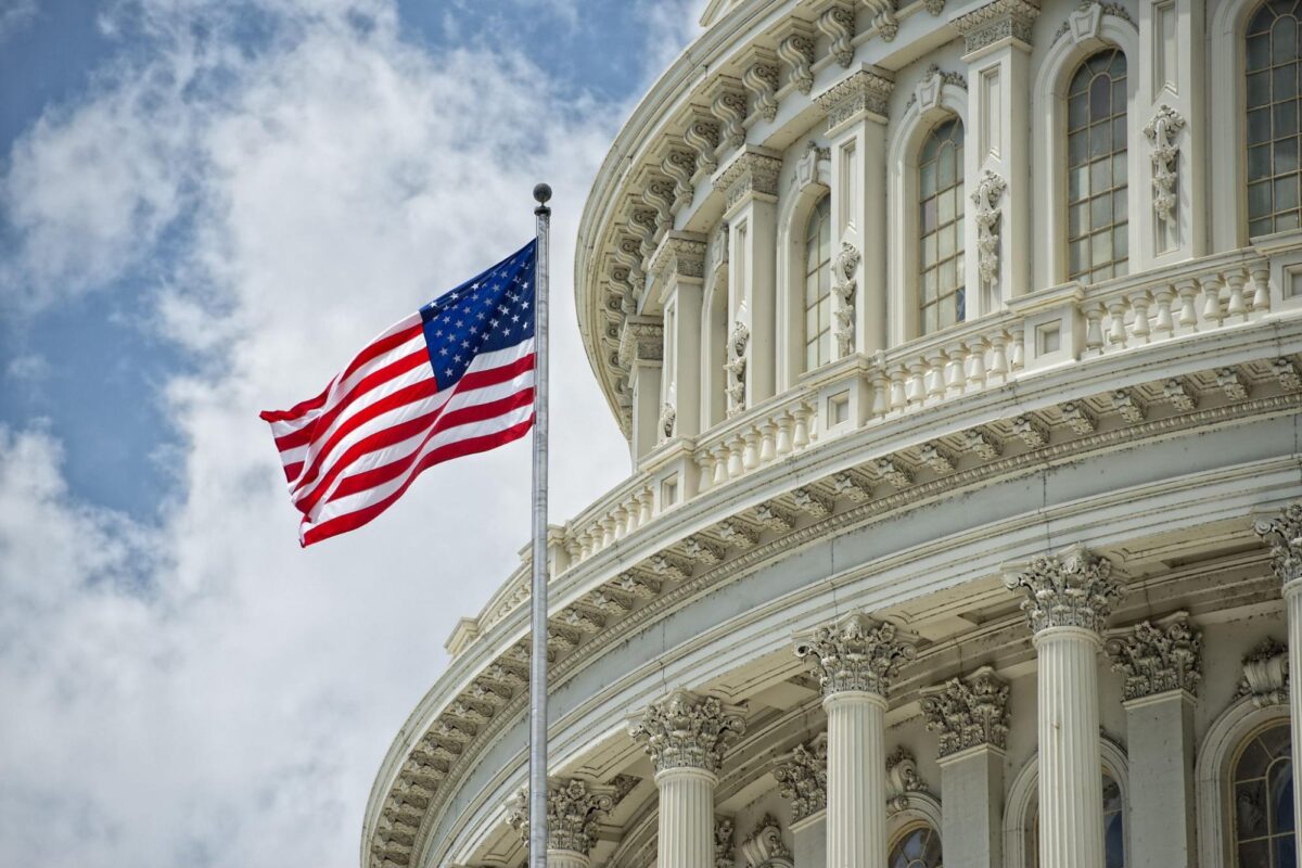 A waving American flag in front of the Washington D.C. Capitol dome.