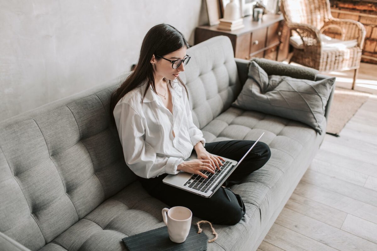 Woman sits on her laptop on her couch composing a 30-day notice letter to her landlord.