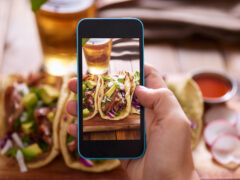 A diner using a phone to photograph the best Mexican food in Denver.