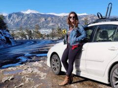 Digital nomad Jess Goudreault stands by her car in Denver, Colorado, with beautiful mountain views in the background.