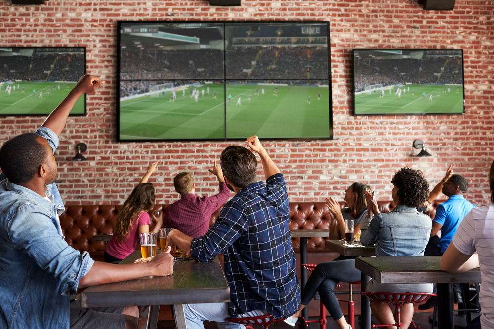 Friends watch a sports game on TV in a sports bar in Charlotte, NC.