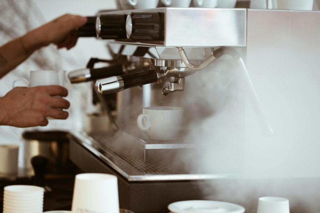 Coffee machine being used, surrounded by steam.