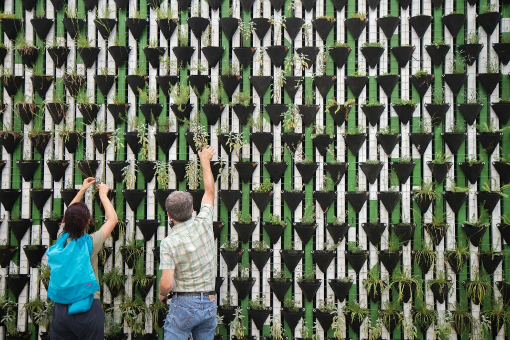 A man and a woman planting plants into a vertical garden