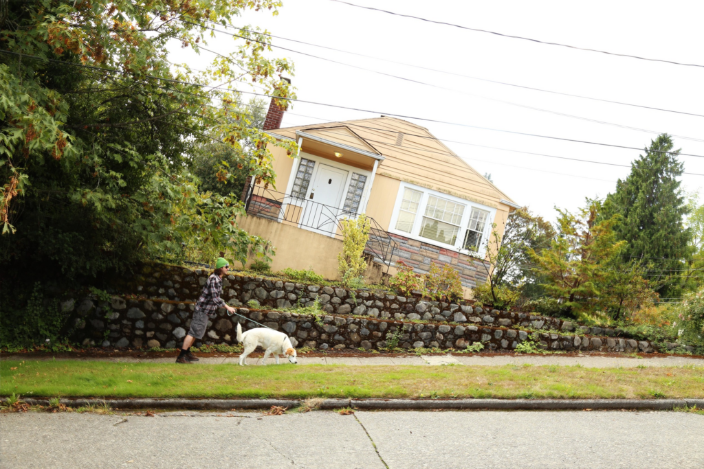A man walking a dog in one of Seattle's hilly streets.